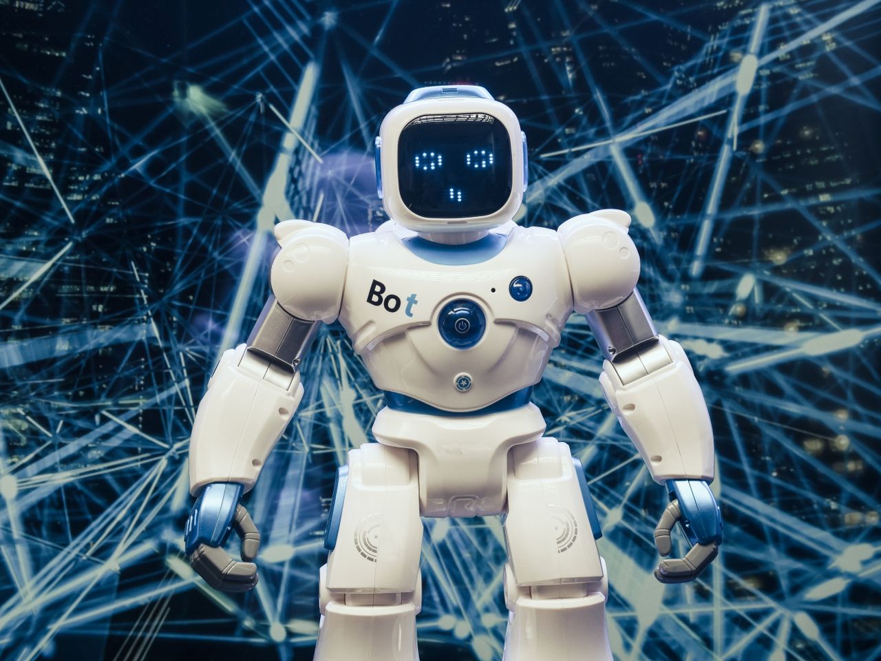 Home A modern humanoid robot with luminous features set against a digital network backdrop.